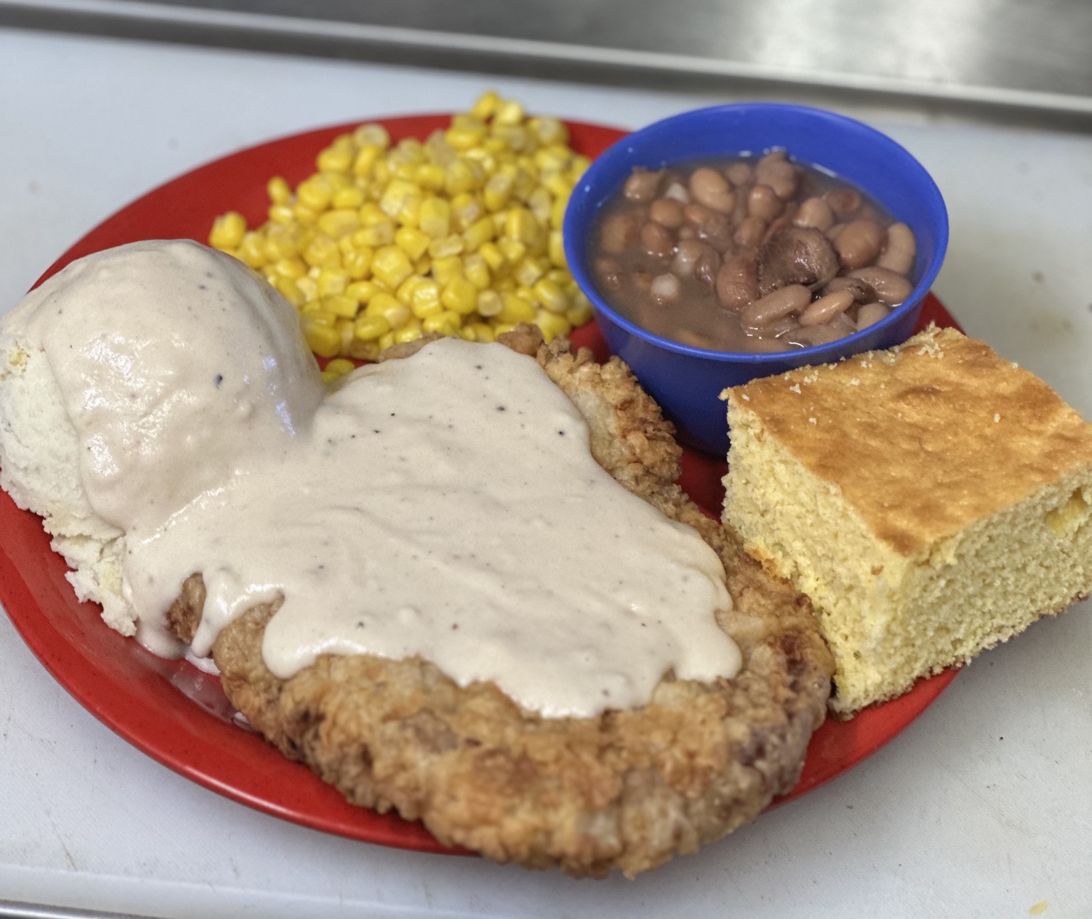 Ernie’s hand-battered chicken fried steak with cream gravy, mashed potatoes, corn, pinto beans, and cornbread